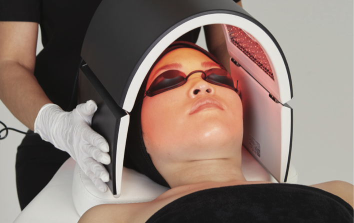 Person liegt auf einer Liege und erhält Lichttherapie im Gesicht